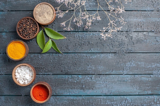 Free photo top view different seasonings inside little pots on dark-blue desk spicy pepper color food edgy