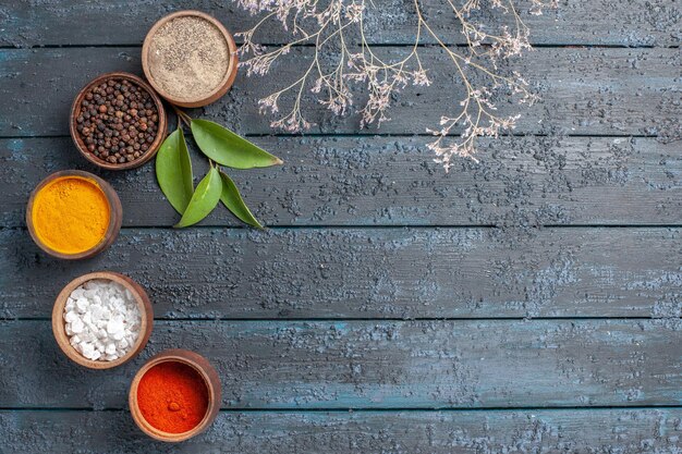 Top view different seasonings inside little pots on dark-blue desk spicy pepper color food edgy