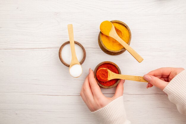 白い机の上の小さな鍋の中のさまざまな調味料の上面図コショウ色の食品スパイシーなホット写真