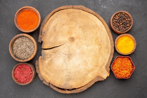 Top view of different seasonings spicy ingredients inside little pots on black