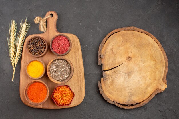 Top view of different seasonings spicy ingredients inside pots on black