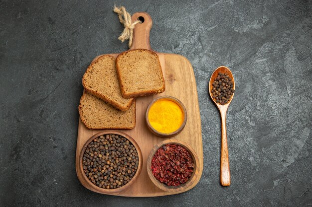 Top view different seasonings with bread loafs on grey desk bread spicy hot