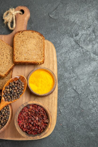 Top view different seasonings with dark bread loafs on grey surface bread spicy hot