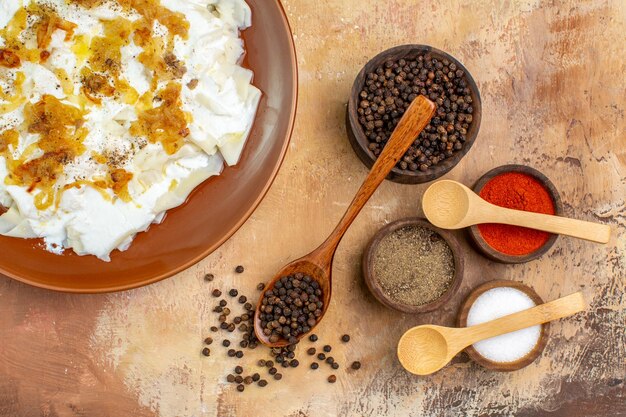 Top view different seasonings with dough slice meal on cream desk