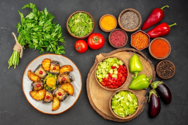 Top view of different seasonings with fresh vegetables on black table