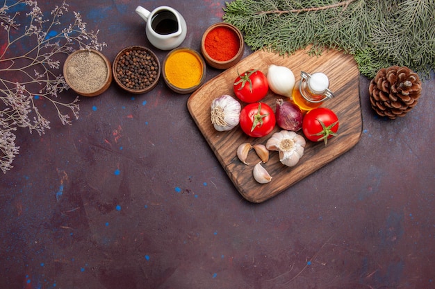 Top view of different seasonings with fresh vegetables on black