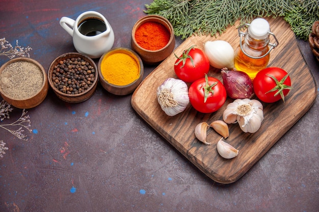 Top view of different seasonings with fresh vegetables on black