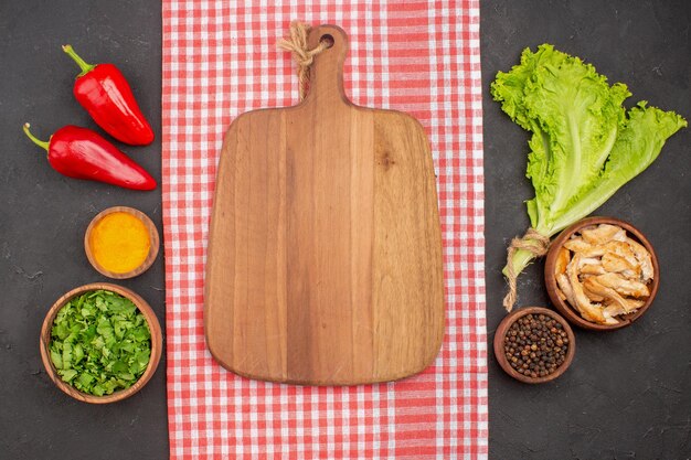 Top view of different seasonings with greens on black