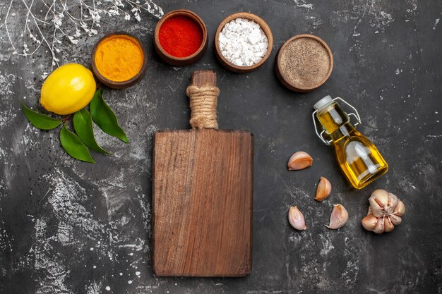 Top view different seasonings with oil and lemon on dark desk spice color pepper