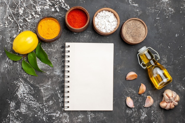 Foto gratuita vista dall'alto diversi condimenti con olio e limone sul pepe di colore delle spezie da tavola scura