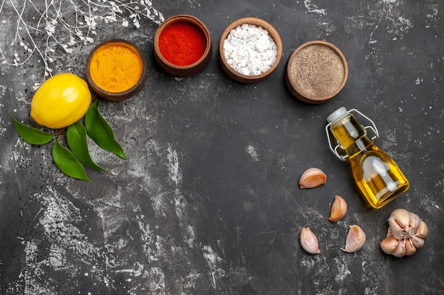 Top view different seasonings with oil and lemon on dark table spice color pepper