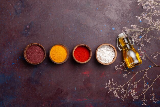 Top view different seasonings with olive oil on dark space