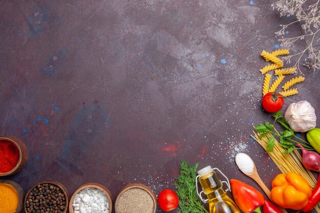 暗い背景の製品ローフードサラダの健康に生パスタを使ったさまざまな調味料の上面図