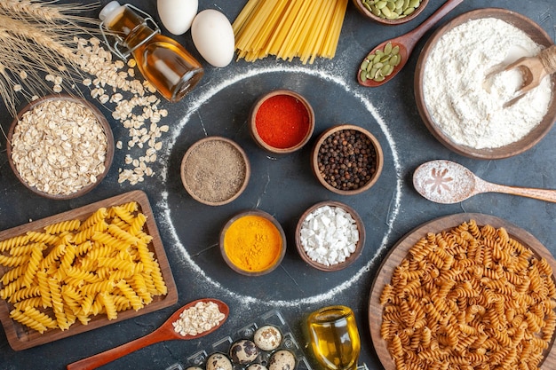 Top view different seasonings with raw pasta eggs and flour on dark background color dough photo meal bake kitchen