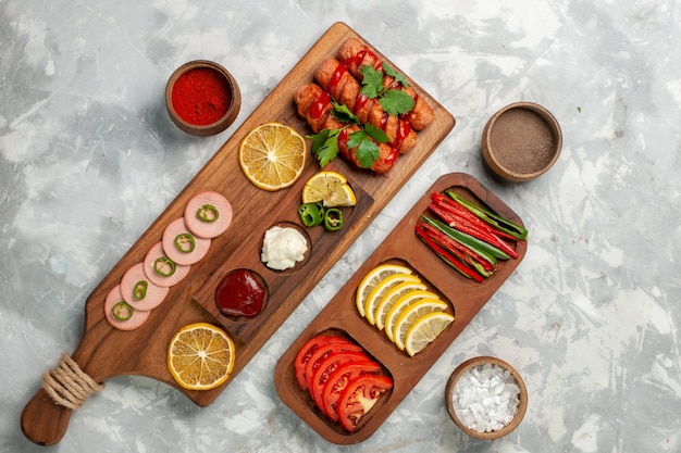 Top view different seasonings with sausages and vegetables on white desk meal food vegetable