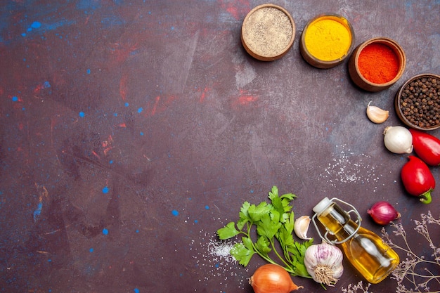 Top view of different seasonings with vegetables on black table