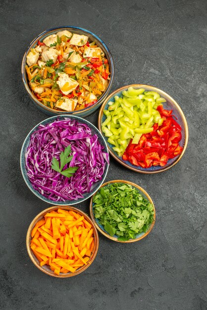 Top view different sliced vegetables with greens on the dark table health diet salad