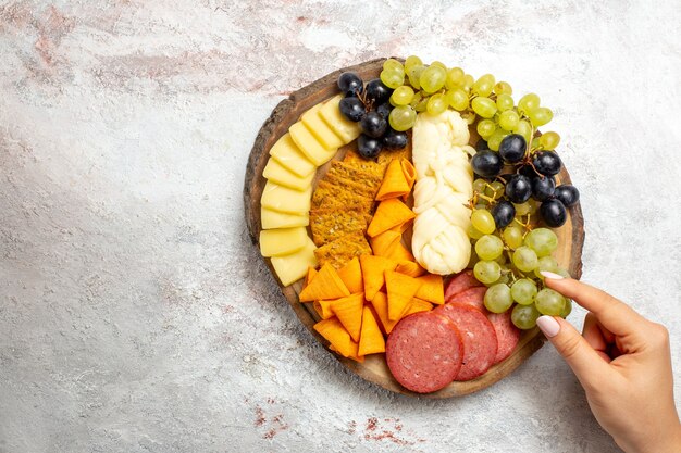 Top view different snacks cips sausages cheese and fresh grapes on a white space