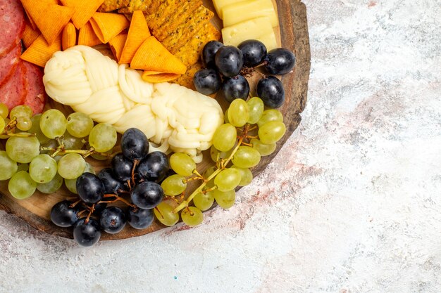 Top view different snacks cips sausages cheese and fresh grapes on white space