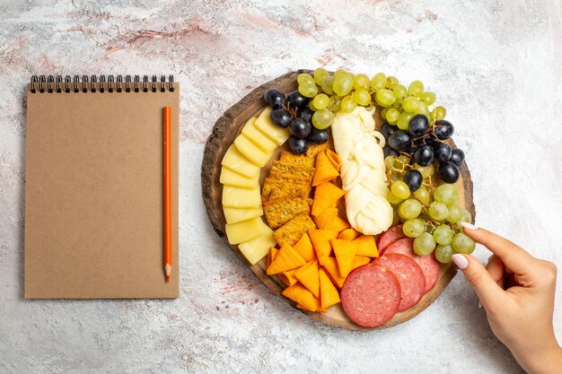 Top view different snacks cips sausages cheese and fresh grapes on white space