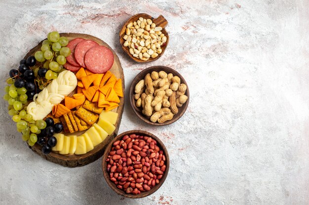 Top view different snacks cips sausages cheese and fresh grapes with nuts on white space