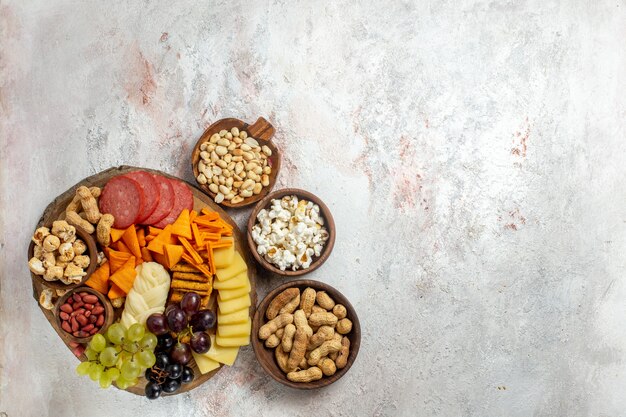 Top view different snacks nuts cips grapes cheese and sausages on a light white background nut snack meal food fruit