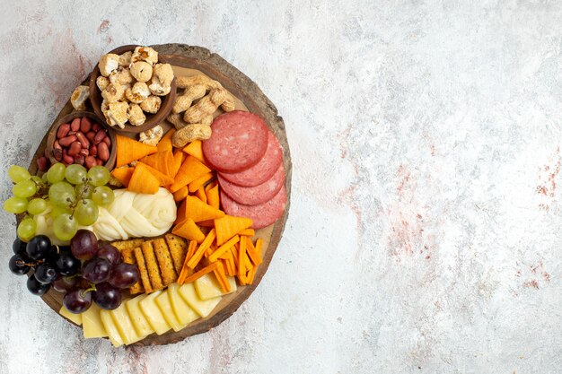 Top view different snacks nuts cips grapes cheese and sausages on the white background nut snack meal food fruits