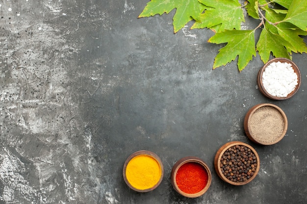 Free photo top view different spices in small bowls salt pepper on grey background