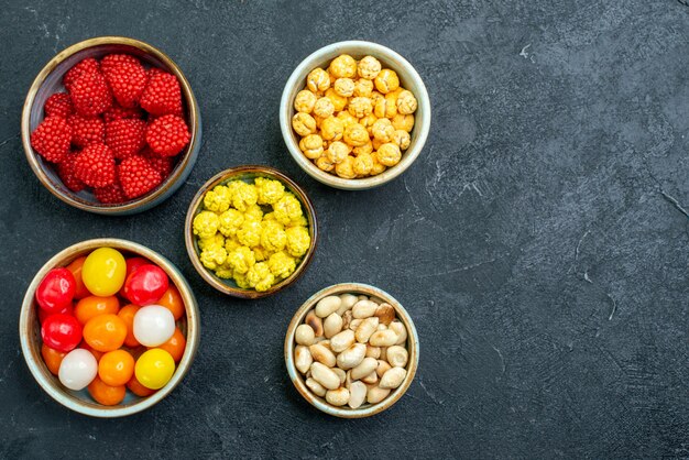 Top view different sweet candies inside pots on dark surface candy sugar bonbon goodie sweet