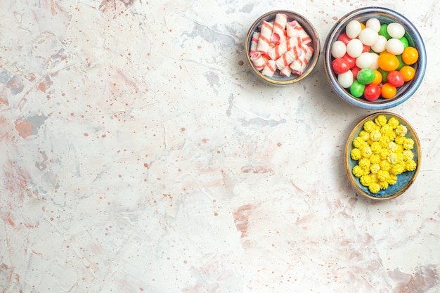 Top view different sweet candies with confitures on a white table color candy sweet