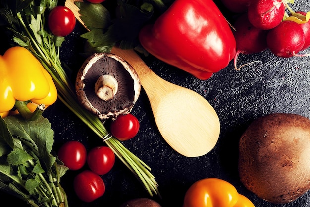 어두운 보드에 있는 다양한 종류의 야채를 위에서 볼 수 있습니다. 빨강 및 노랑 후추, 버섯, 체리 및 채소