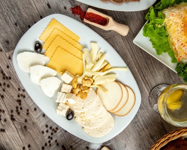 Top view of different types of cheese on a white plate on table