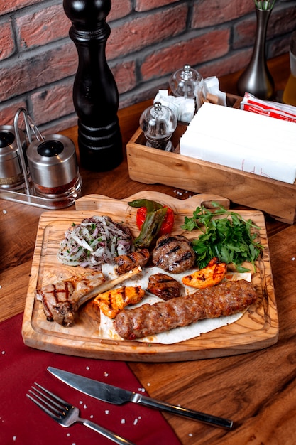 Top view of different types of kebab witj onion and herbs on a wooden board