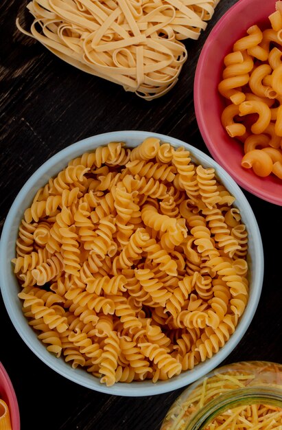 Top view of different types of pasta on wooden surface