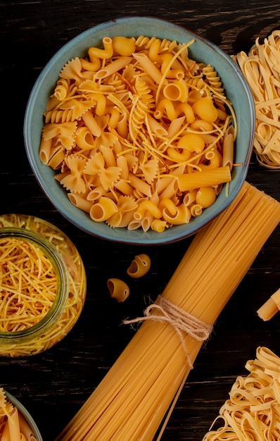 Top view of different types of pasta on wooden surface