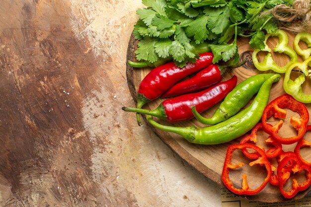 Top view different vegetables cut into pieces on round tree wood board on raw sienna background