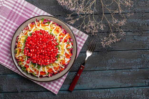 Top view dish and fork plate of appetizing dish on the tablecloth next to the tree branches and fork on the grey table