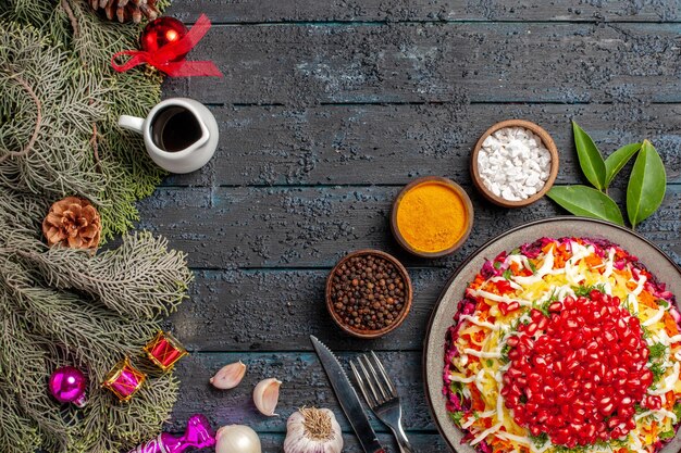 Top view dish and spruce branches appetizing Christmas dish with lemon garlic bowl of oil and spices next to the fork knife and spruce branches with cones