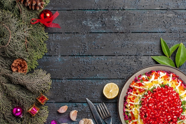 Free photo top view dish and spruce branches appetizing christmas dish with lemon garlic fork knife and spruce branches with cones