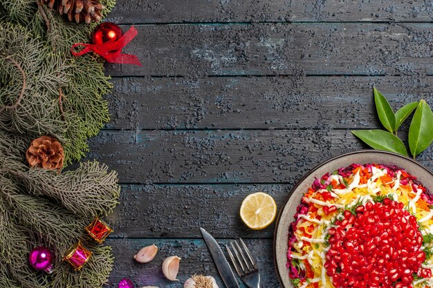 Top view dish and spruce branches appetizing Christmas dish with lemon garlic fork knife and spruce branches with cones