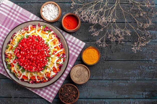 Top view dish and tablecloth spices and tree branches next to the checkered tablecloth and plate of food