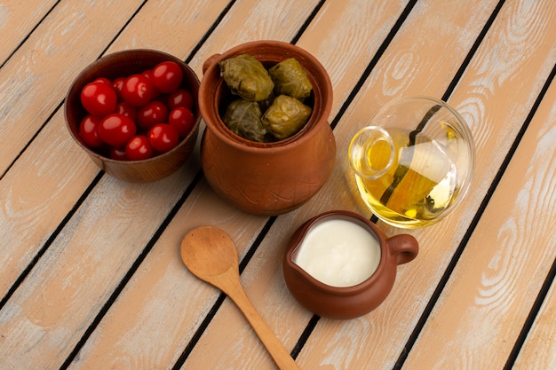 Долма, красные помидоры, оливковое масло и йогурт на деревянном деревенском столе