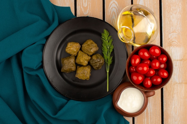 Free photo top view dolma green along with olive oil and yogurt on the wooden floor