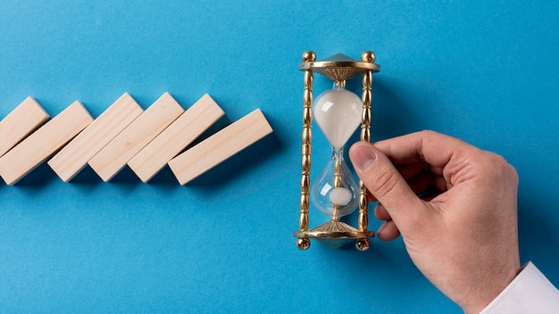 Top view of domino pieces with businessman holding hourglass