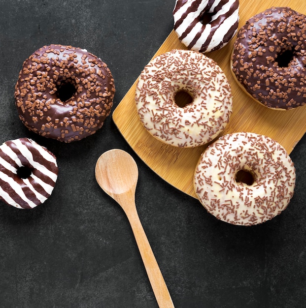 Top view of donuts on chopping board with wooden spoon