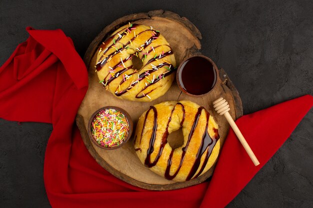 вид сверху пончики сладкие вкусные вкусные на коричневом столе и темном фоне
