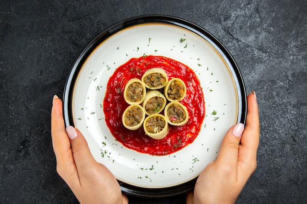 Vista dall'alto impasto con fette di carne affettata con salsa di pomodoro su uno spazio grigio