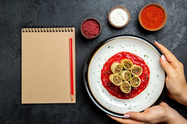 Вид сверху на тесто с мясом, нарезанным томатным соусом и приправами на сером пространстве