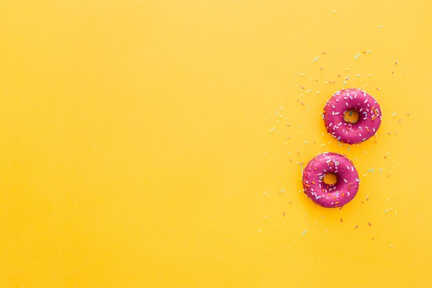 Top view of doughnut in pink icing on yellow background