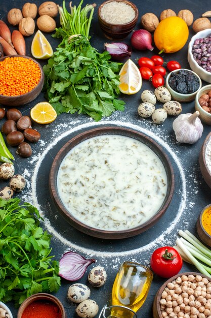 Top view dovga soup tomatoes parsley oil bottle eggs green onion rice in bowl on table